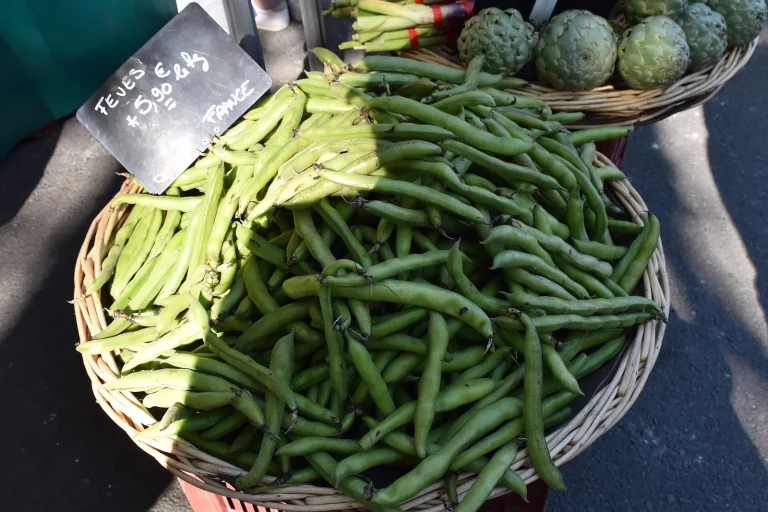 Gousses vertes en vrac dans un panier sur un étal de marché